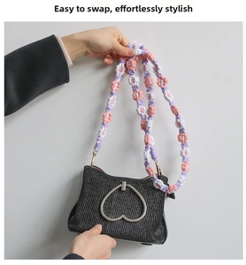 Detail of colorful woven floral strap with pink and purple flowers on a black handbag
