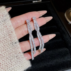 Macro detail of long silver-tone tassel earrings featuring a crystal spiral tassel design