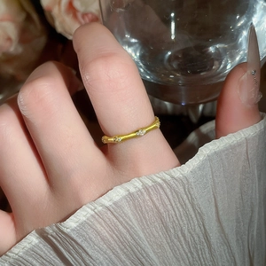Detailed view of a gold bamboo-style open bracelet with sparkling zircon accents on wrist