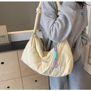 Detail view of large quilted canvas tote bag in creamy yellow with rope charm accessories