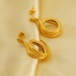 Macro shot of gold snake earrings featuring detailed scale texture on yellow silk