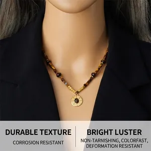 Detail of tiger eye stone necklace with gold pendant on black blazer model