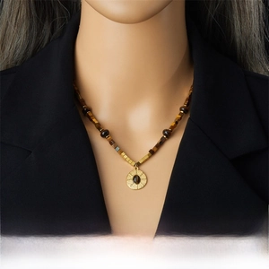 Detail of tiger eye stone necklace with gold pendant on black blazer model