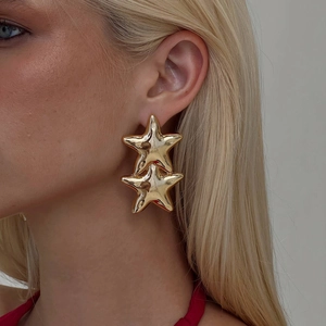 Close-up of a double-layered golden starfish earring worn by a model in a professional shot