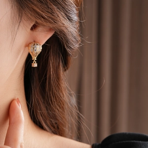 Gros plan de boucles d'oreilles montgolfière dorées avec zircons portées par un mannequin