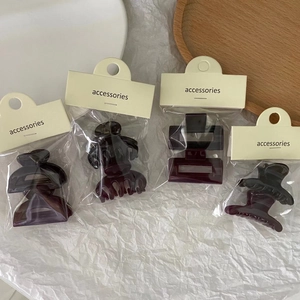 Detailed view of four solid dark purple jelly hair clips individually packed on cardboards