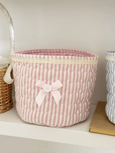 Close-up of pink striped quilted fabric storage basket with lace trim and bow accent