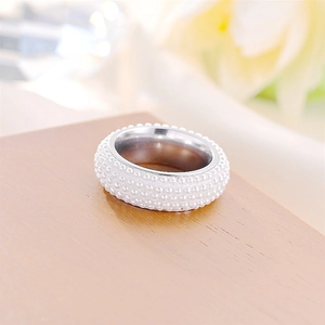 Dettaglio ravvicinato di un anello in acciaio inox con cinque file di perle bianche
