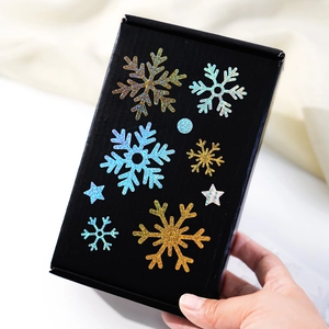 Detail of glitter snowflake and star stickers on a black gift box for DIY decor