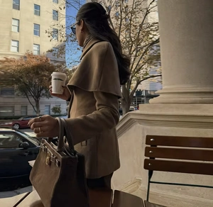 Detail of brown wool cape coat paired with a luxury leather tote bag on city street
