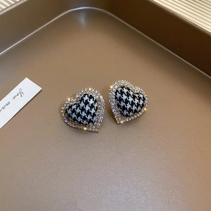 Detailed view of houndstooth heart earrings with sparkling rhinestone edge and gold finish