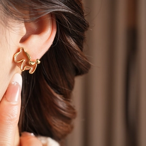 Detail of dachshund puppy stud earring in gold metal and reddish-brown enamel
