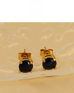 Detail of 18K gold plated round earrings featuring deep blue zircon in four-prong setting