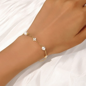 Detail of a gold clover bracelet with pearls and crystals on a silk background