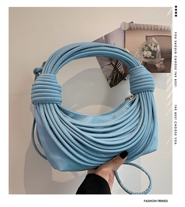 Detail of light blue crescent shoulder bag featuring unique layered rope texture and gold zipper