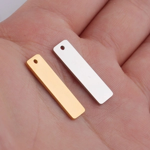 Detailed view of silver and gold rectangular stainless steel pendants held by hand