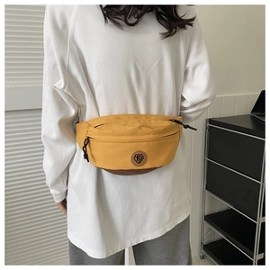 Detail of a yellow and brown fanny pack with FS logo worn by a model in casual white hoodie