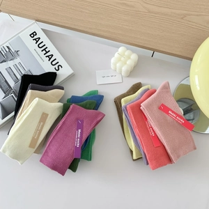 Flat lay of colorful ribbed cotton socks in various shades with stylish brand packaging