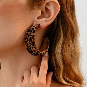 Close-up of a large leopard print flocking geometric C-shaped hoop earring on a model