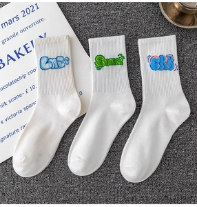 Close-up of white cotton sports socks with blue and green embroidered graffiti typography