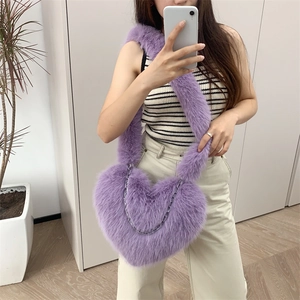 Purple plush heart-shaped crossbody bag with metallic chain strap shown on model