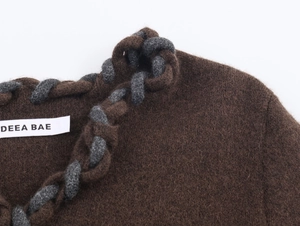 Vue macro d'un cardigan marron avec bordure en corde tressée bicolore et étiquette