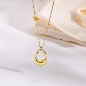 Elegant gold irregular abstract pendant necklace on white background with silk fabric