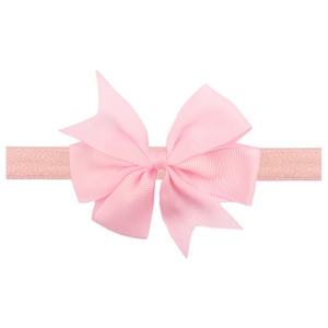 Close-up of pink satin ribbon bow with elastic headband for infants and newborns