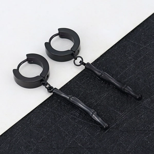 Detail of matte black bamboo-shaped pendant earrings with round hoops on textured background