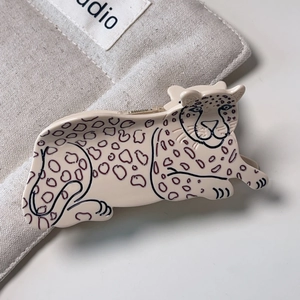 Close-up of leopard-shaped acetate hair claw clip on beige canvas fabric background