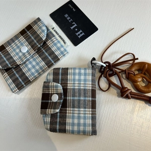 Detail of plaid canvas pouches with button closure and biscuit-shaped wooden charm