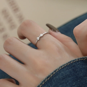 S925 sterling silver bow knot ring with zircon stones worn on finger on denim background