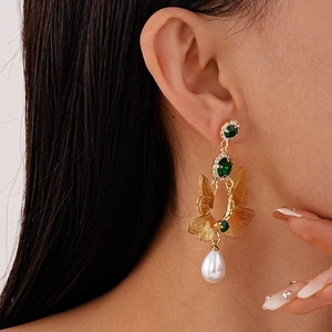 Detail of vintage double-layer butterfly earrings with green stones and pearl droplets