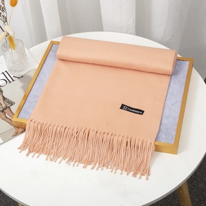 Thick light orange cashmere-like scarf with fringe tassels on a decorative tray