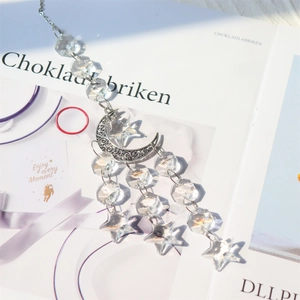 Macro shot of a bohemian crystal suncatcher with crescent moon and star prisms on a book