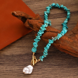 Detail of bohemian turquoise beaded necklace with baroque pearl and golden toggle clasp