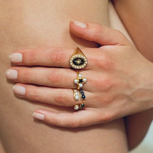 Detailed close-up of vintage gold rings with pearls and star motifs on a hand