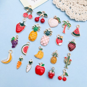 Flat lay of colorful fruit alloy charms featuring strawberry, cherry, and pineapple designs