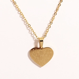 Macro detail of golden heart pendant featuring vertical textured lines and polished finish