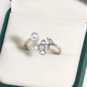 Macro shot of silver ring with white pearl and floral enamel in green velvet box