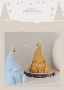 Detailed view of handmade Christmas gnome candles in blue and yellow with gold bells