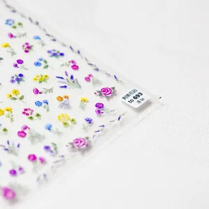 Close-up of thin embroidery style nail stickers with purple, pink and yellow floral patterns