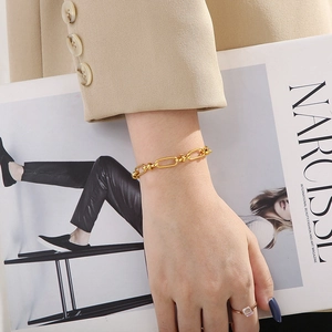 Macro detail of a trendy gold knot design stainless steel chain bracelet on a wrist