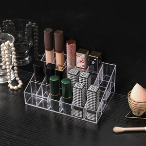 Clear acrylic lipstick organizer with multi-grid design on a sleek black vanity setup