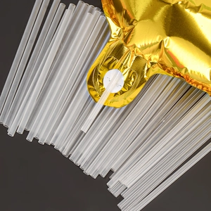 Détail de pailles en plastique transparent insérées dans les valves de ballons dorés
