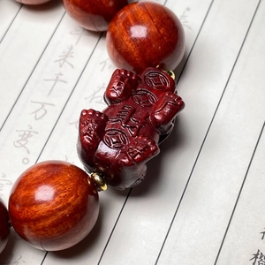Macro di perle in legno di sandalo rosso intagliato e ciondolo Pixiu su sfondo etnico