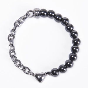 Detail of silver heart magnetic clasp connecting black beads and steel chain link bracelet