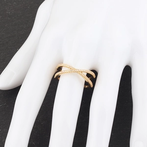 Detail of a gold X-shaped crisscross ring with micro-paved white zircons on a model