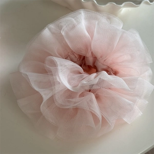 Close-up of pink layered lace scrunchie with airy tulle texture on a white tray