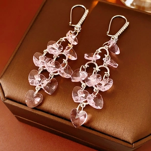Detailed close-up of silver earrings with pink crystal hearts and zircon tassel fringe